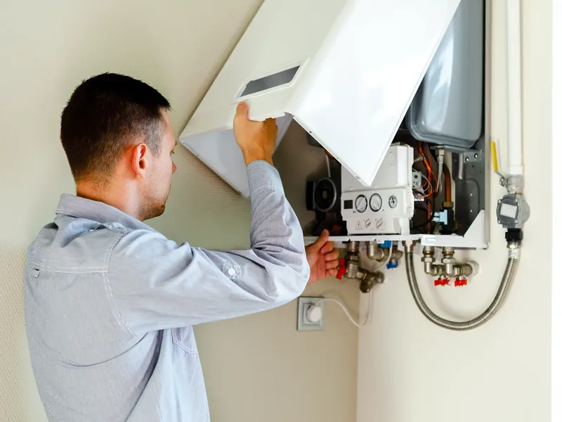 Heating engineer installing and wiring a wall-mounted boiler
